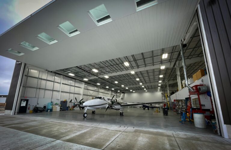 Light aircraft parked inside a spacious modern hangar used for private aviation.