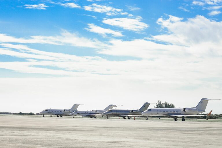 Row of private jets parked on a clear day at an open runway, showcasing aviation and luxury travel.